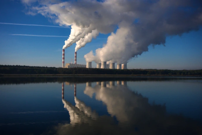 Smoke stacks rise from a factory near a body of water